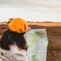 野原に向かって地図を広げる女性の画像